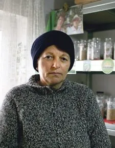 Eine Frau neben Regalen mit Gläsern und Behältern.
