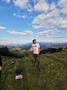 Charlie Ottley auf einem grasbewachsenen Höhenrücken vor einer Berglandschaft.