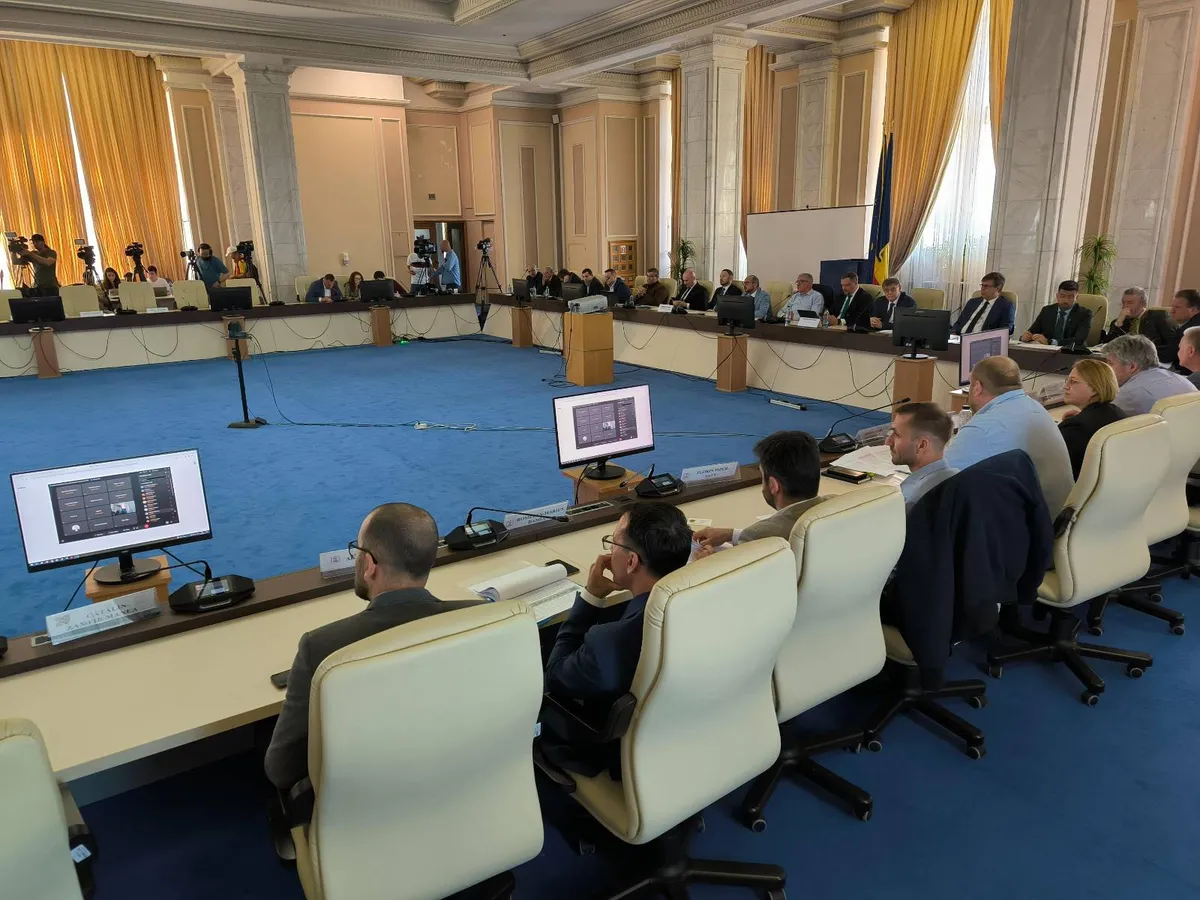 Participants seated around a conference table in a room with yellow curtains.